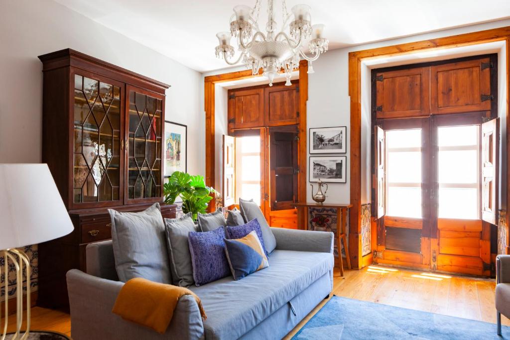 リスボンにあるAlfama Terrace Apartment With Authentic XVIII Tiles And Historic Notes 3 Bedrooms & 2 Bathrooms ACのリビングルーム(青いソファ、シャンデリア付)