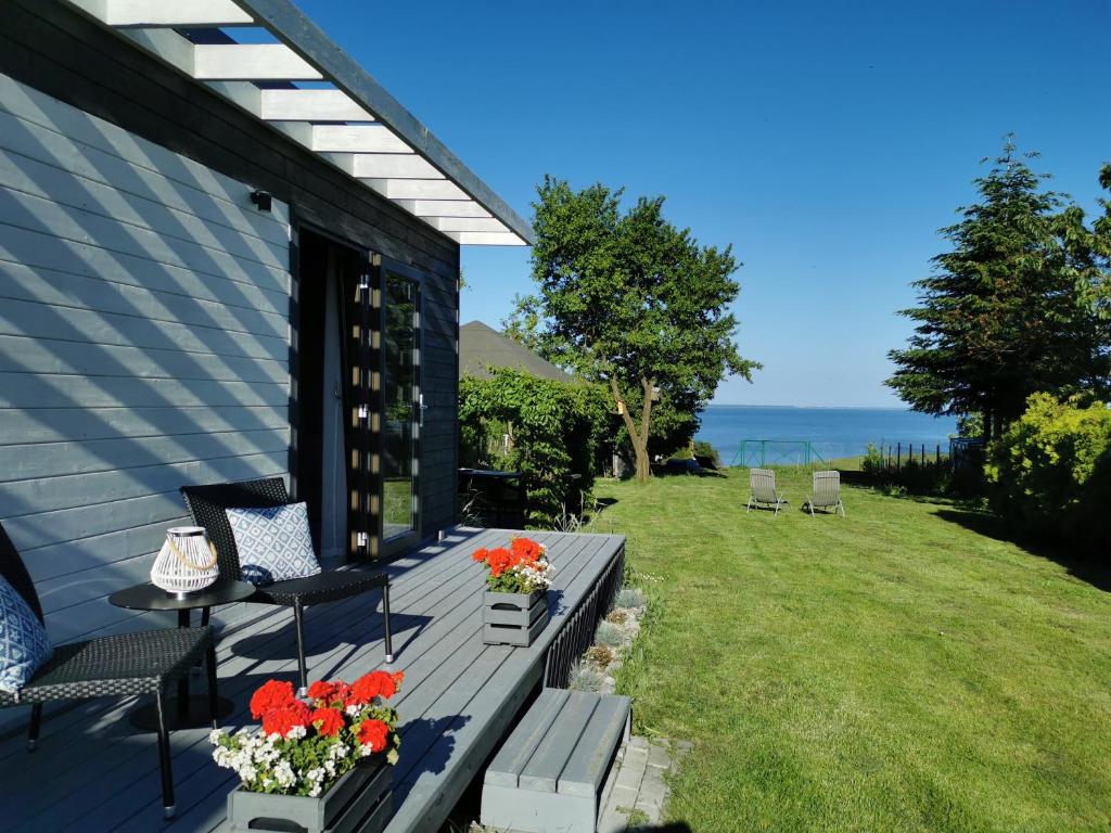 eine Terrasse mit einem Tisch, Stühlen und Meerblick in der Unterkunft Domek Morski in Swarzewo