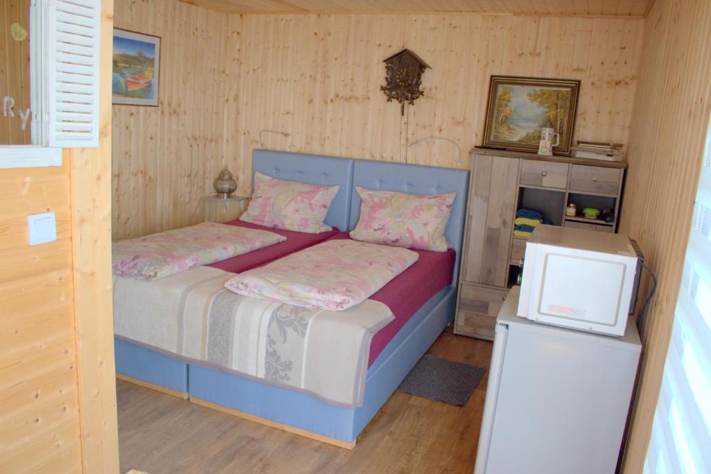 ein kleines Schlafzimmer mit einem blauen Bett und rosa Kissen in der Unterkunft Haus am See in Rust