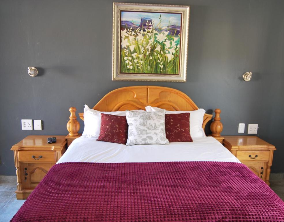 a bedroom with a large bed with red and white pillows at 14 Cluster Cottages in George