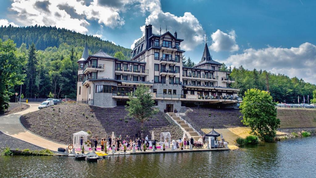 um grande edifício à beira de um lago em Retro Riverside Wellness Resort em Karlovy Vary