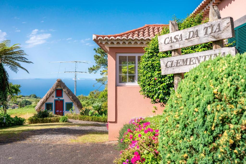 un panneau devant une petite maison fleurie dans l'établissement Casa da Tia Clementina, à Santana