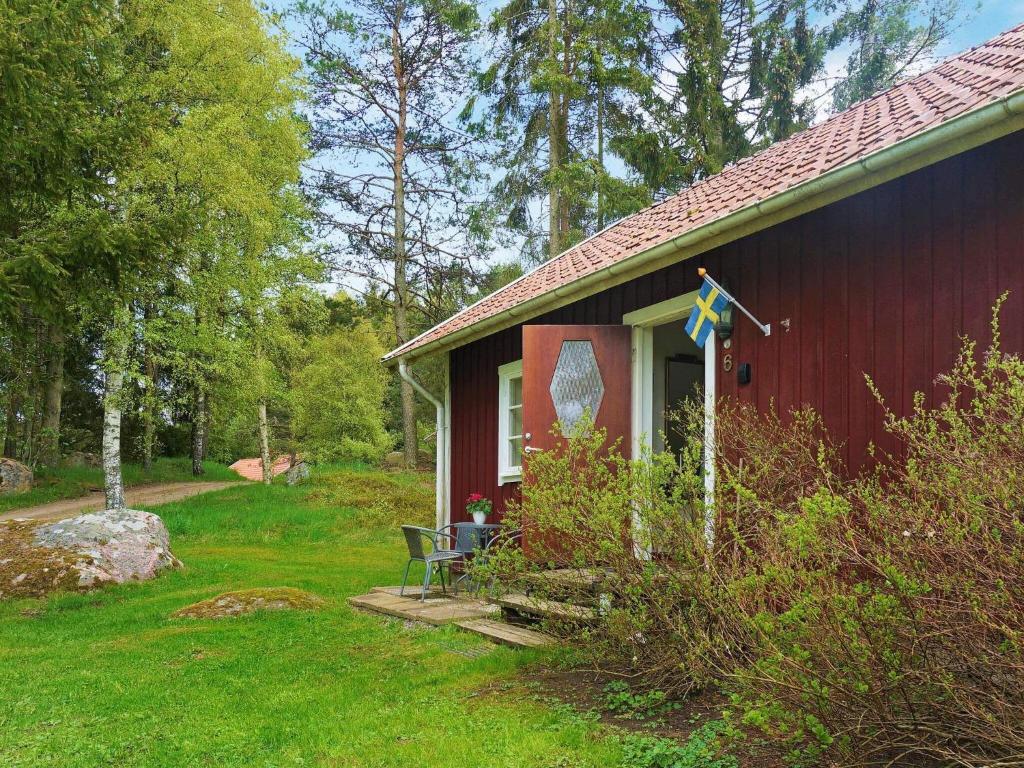 una casa roja con una bandera en la parte delantera en Two-Bedroom Holiday home in Åsarp 3, en Åsarp