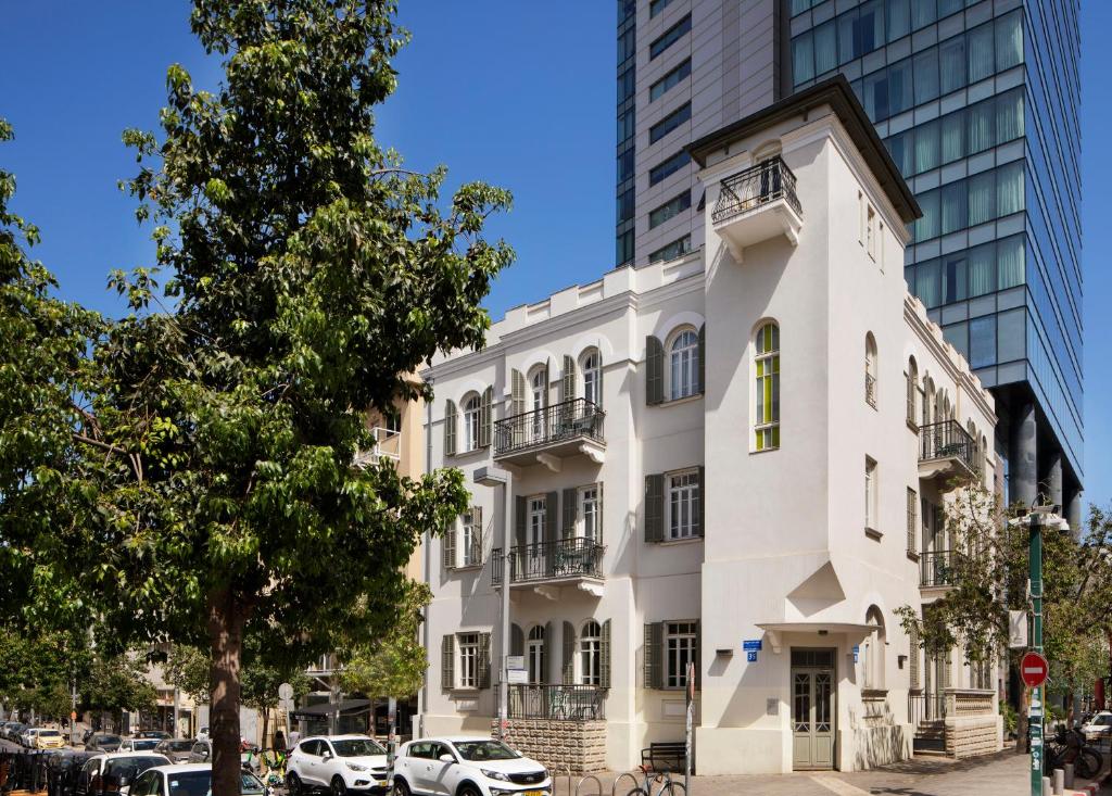 un bâtiment blanc devant un grand bâtiment dans l'établissement Bachar House, à Tel Aviv