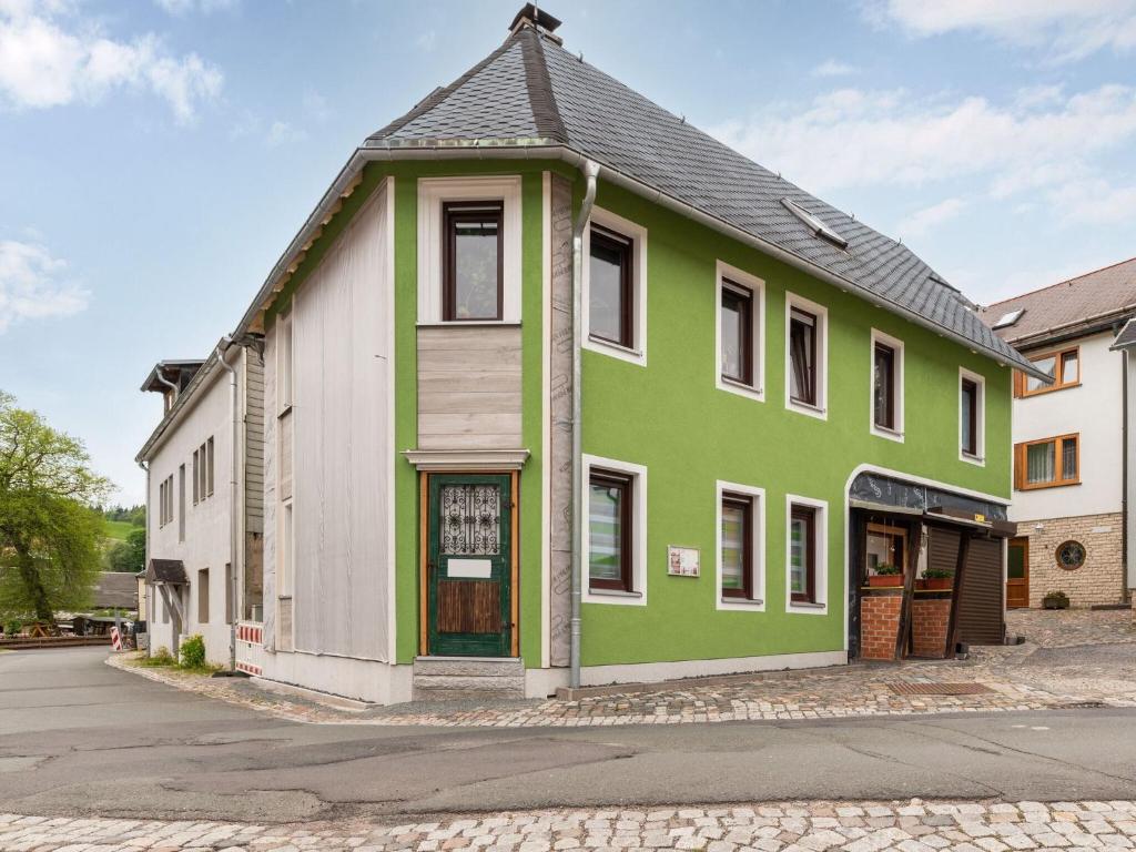 un bâtiment vert et blanc sur le côté d'une rue dans l'établissement Bright apartment in a district of Ilmenau, à Stützerbach
