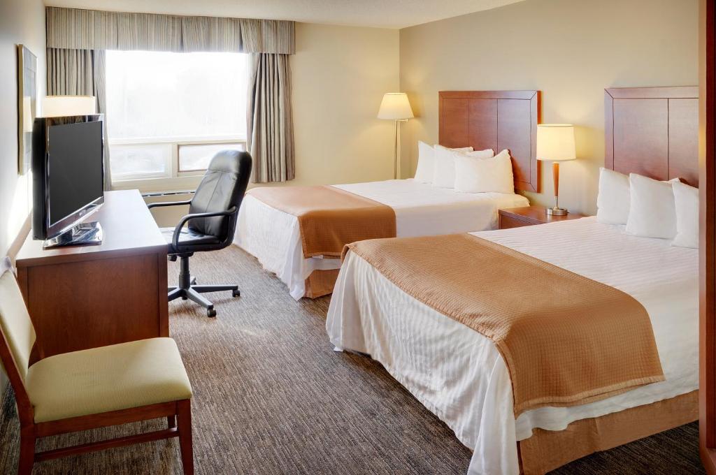 a hotel room with two beds and a desk and a television at Quality Inn in North Bay