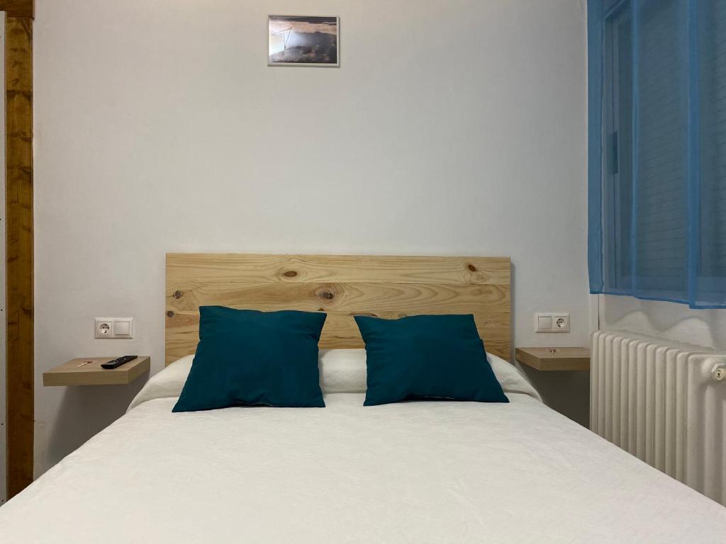 a bedroom with a bed with two blue pillows at Hostal Grimaldos in Riópar
