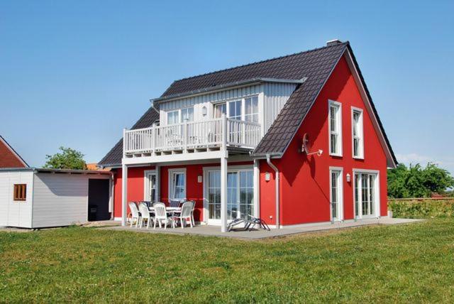 a red and white house with a table and chairs at "Tau Hus" im "Roden Hus" in Timmendorf