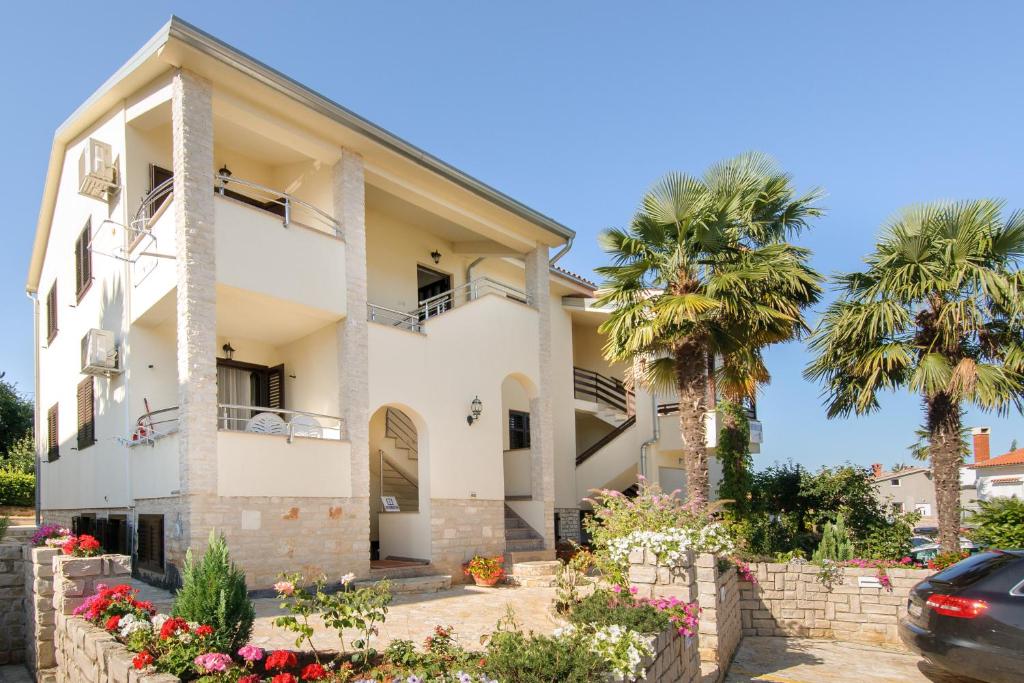 dom z palmami i samochód zaparkowany przed budynkiem w obiekcie Apartmani Lorena w Poreču