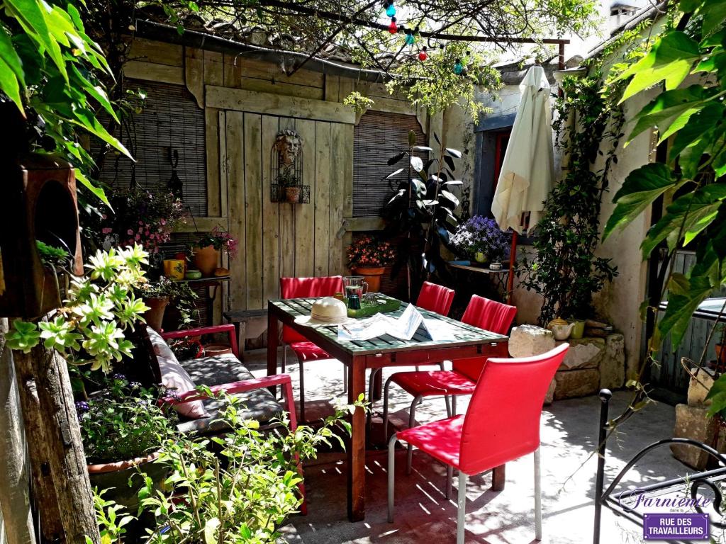patio ze stołem i czerwonymi krzesłami w obiekcie Chambre d'hôte Farniente w mieście Aigues-Mortes