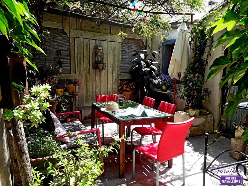 a patio with a table and red chairs at Chambre d'hôte Farniente in Aigues-Mortes