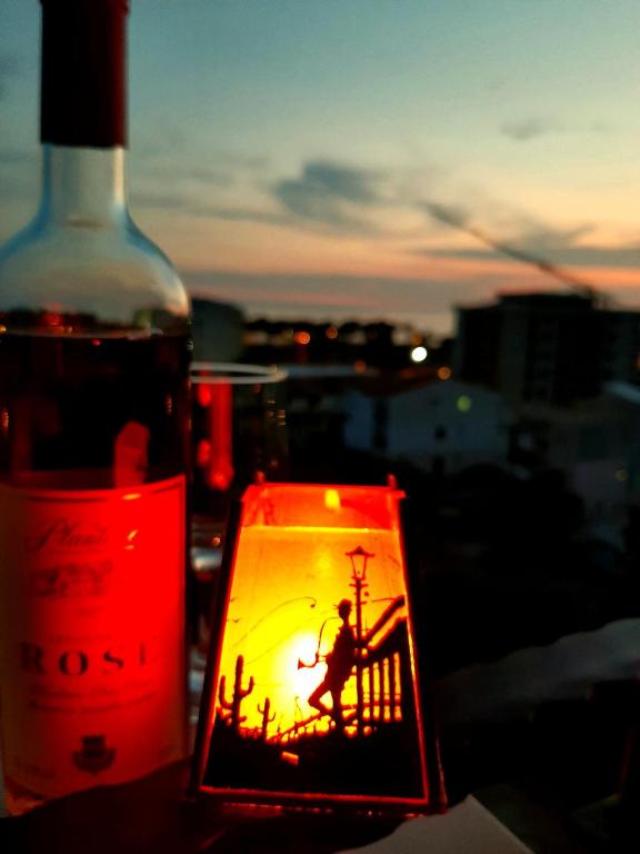 a bottle of wine and a candle next to a window at Apolon Apart in Bar, Susanj