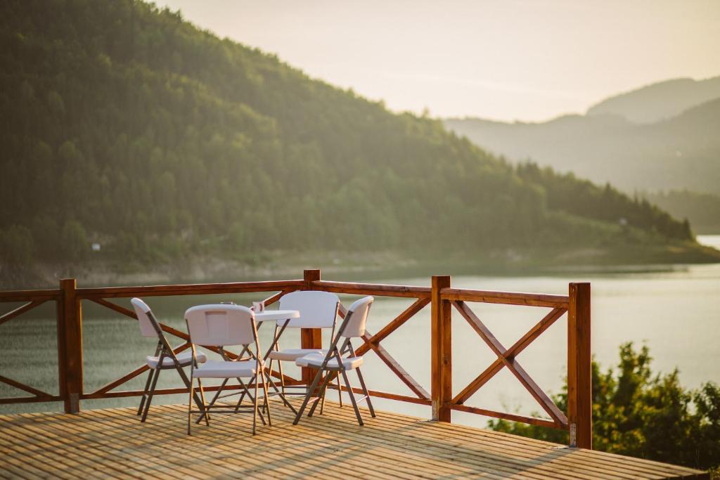 three chairs and a table on a deck overlooking a lake at Zoranovi konaci in Jevtići