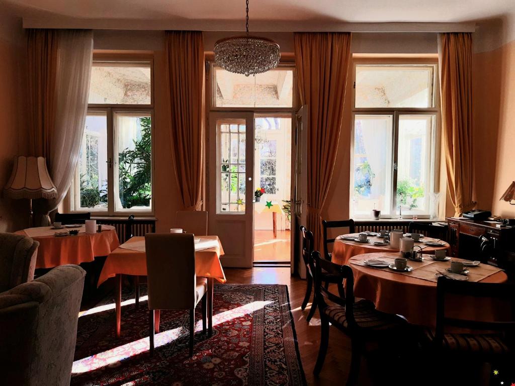 a dining room with tables and chairs and windows at Pension Villa Inge in Baden