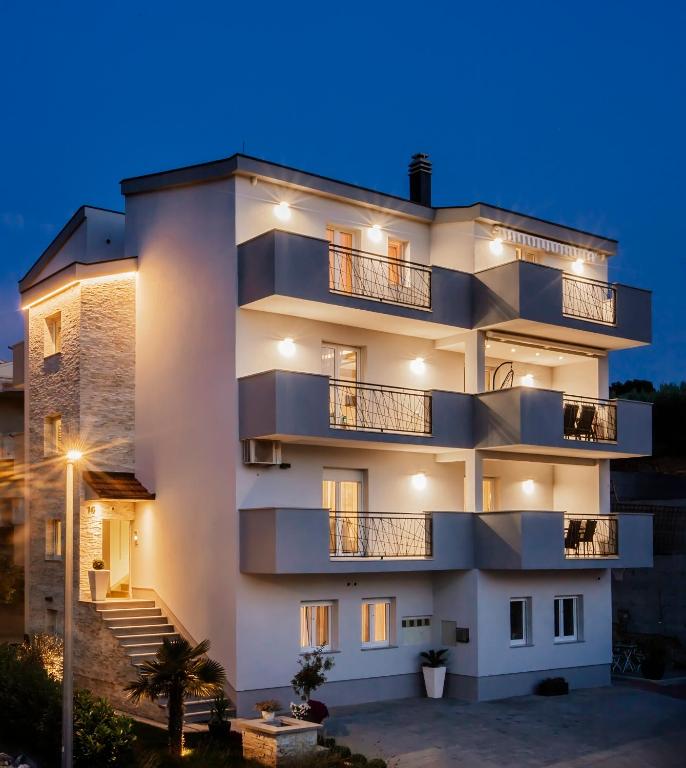 a large white building with balconies at night at Apartments Kolovrat in Podstrana