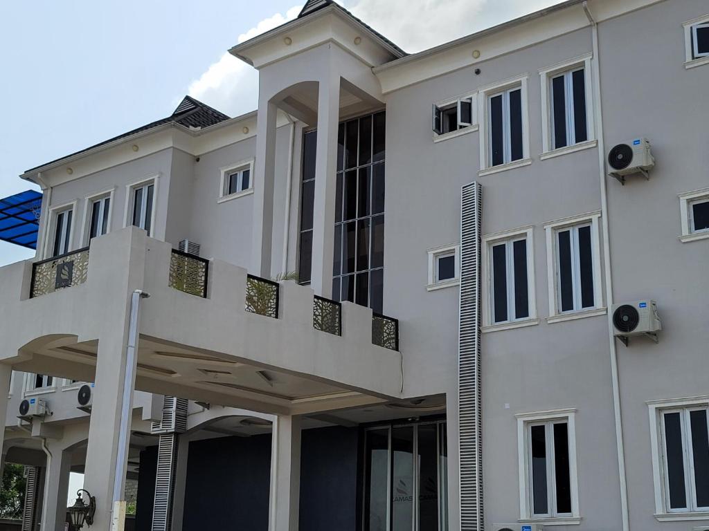 - un bâtiment blanc avec un balcon au-dessus dans l'établissement Camas Hotel & Suite Asero Abeokuta, à Abeokuta
