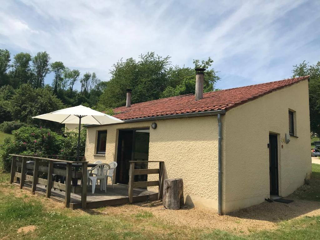 a small building with an umbrella and a deck at Le repaire des hérissons Vallée de Rabais in Virton