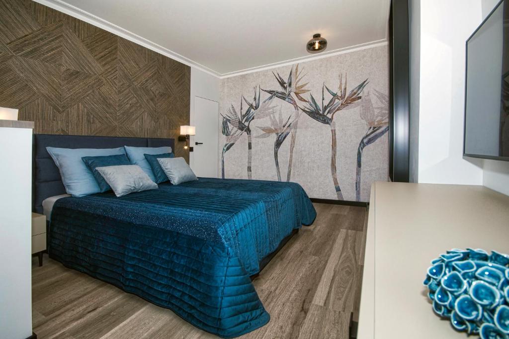 a bedroom with a blue bed and a painting on the wall at ApartPark ALBUS 401 SEA VIEW above the trees in Świnoujście