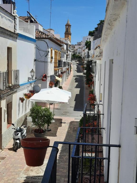 an alley with white buildings and a white umbrella at Apartamento en casco histórico in Estepona