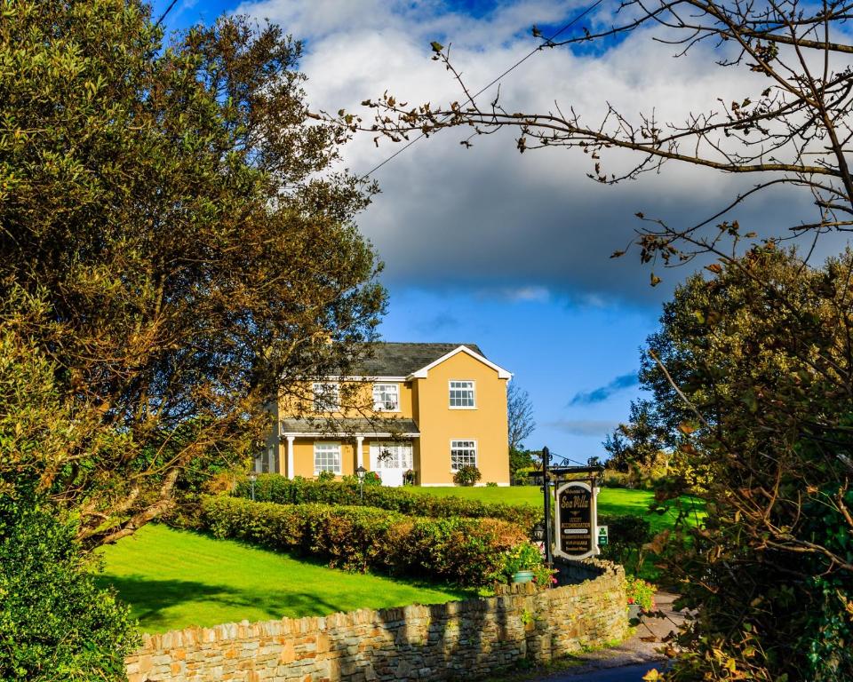 a yellow house on a hill with a stone wall at Sea Villa in Ardgroom