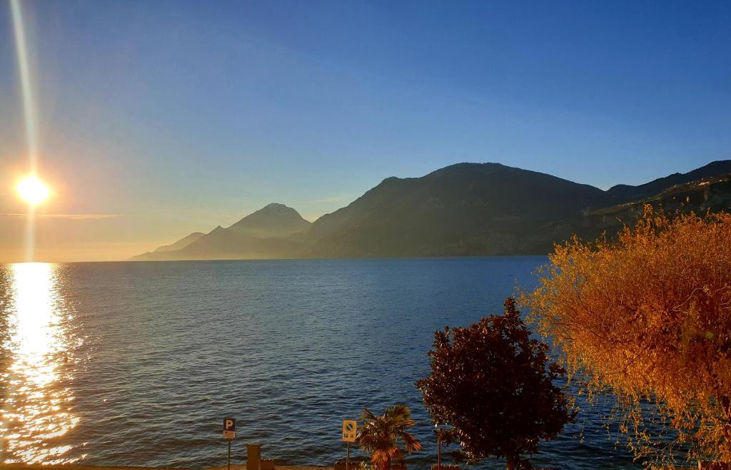 um pôr-do-sol sobre um grande corpo de água com montanhas em Assenza Lake Front Sweet Apartment em Brenzone sul Garda