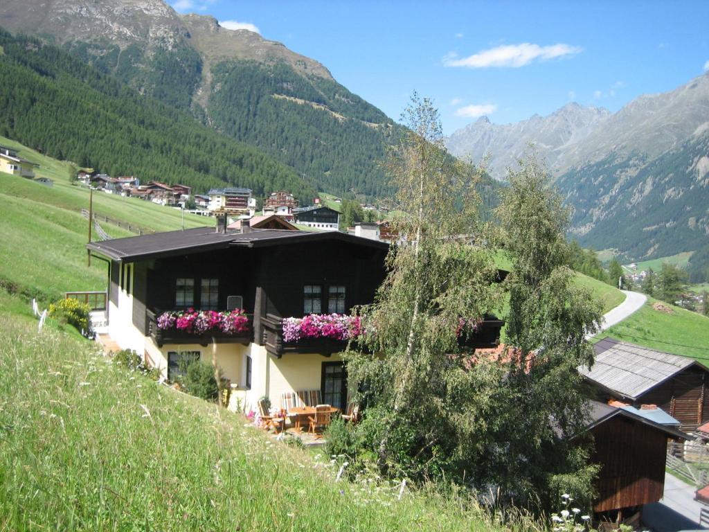 a house on a hill with mountains in the background at Appartement Renate in Sölden