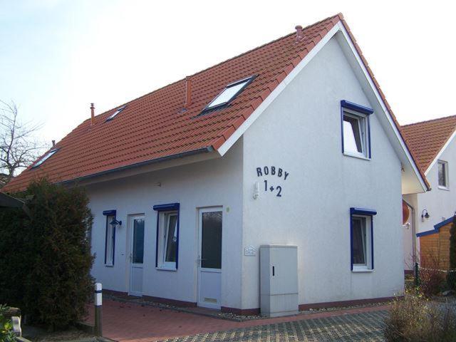 a white house with a red roof with writing on it at Robby1 in Kaltenhof