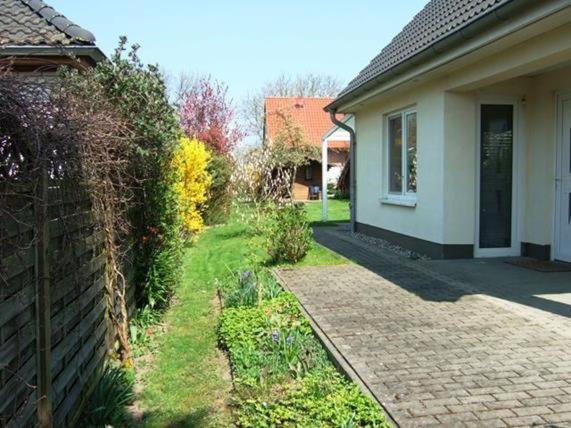 a house with a brick walkway next to a yard at Fenster in Kaltenhof