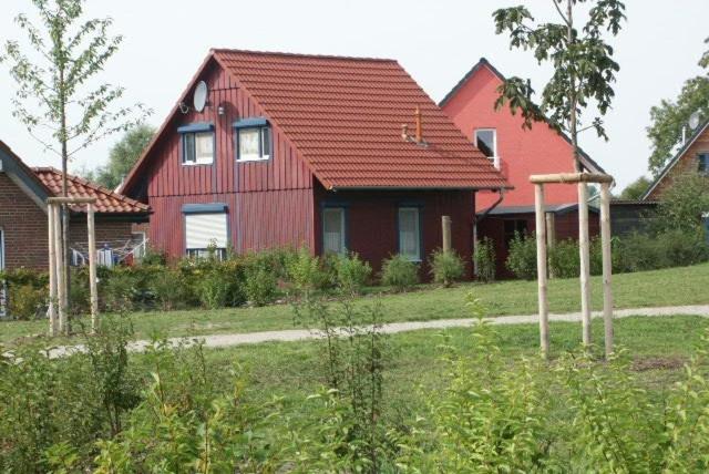 a red house with a red roof in a yard at Hexenhäuschen in Kaltenhof