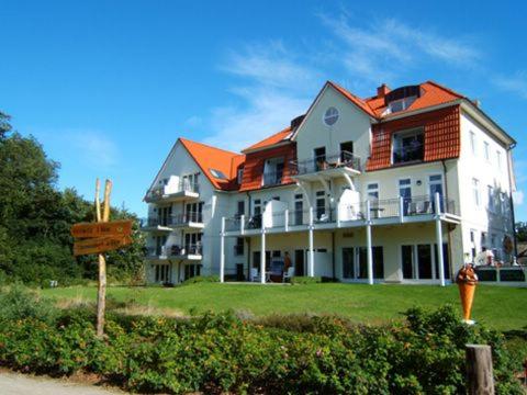 a large white house with an orange roof at Ostseeblick Ferienwohnung in Am Schwarzen Busch