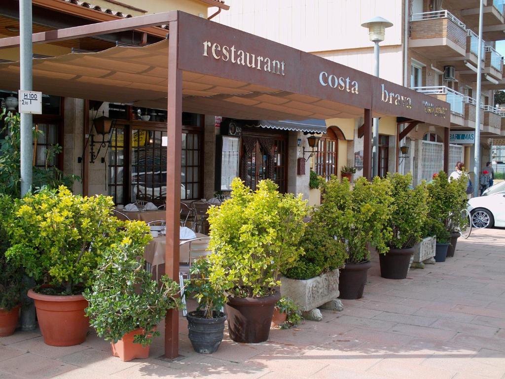 a restaurant with potted plants in front of a building at Pensió Costa Brava in Sant Antoni de Calonge