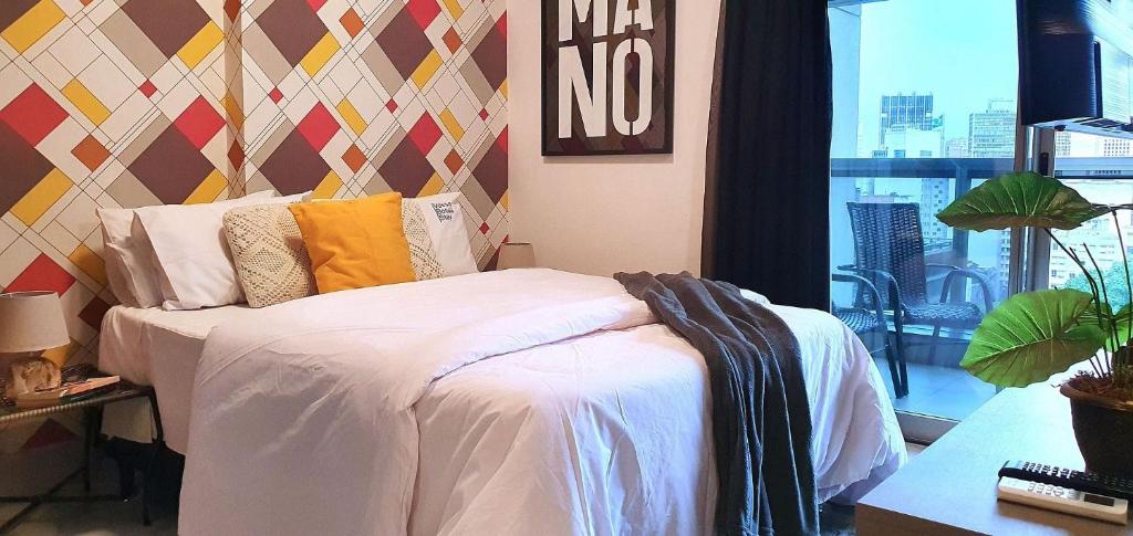 um quarto com uma cama com lençóis brancos e almofadas amarelas em Vossa Bossa Downtown Republica em São Paulo