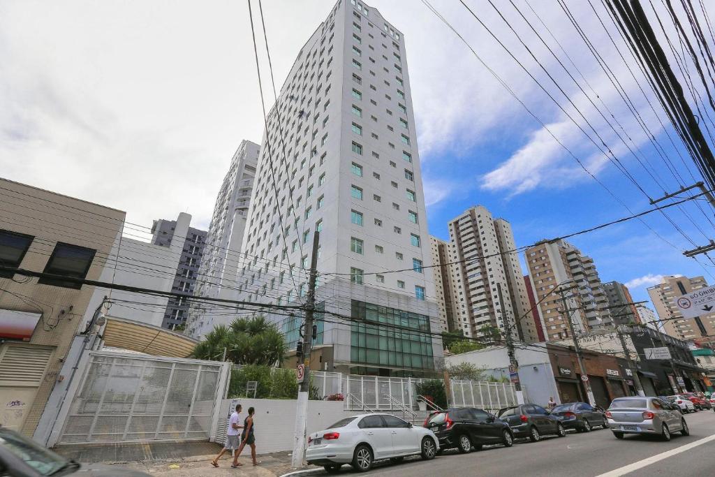 un edificio blanco alto con coches estacionados en una ciudad en Vossa Bossa Pinheiros Style, en São Paulo