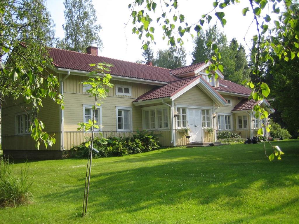 una casa con un césped verde delante de ella en Rauhalan kievari, en Kärsämäki