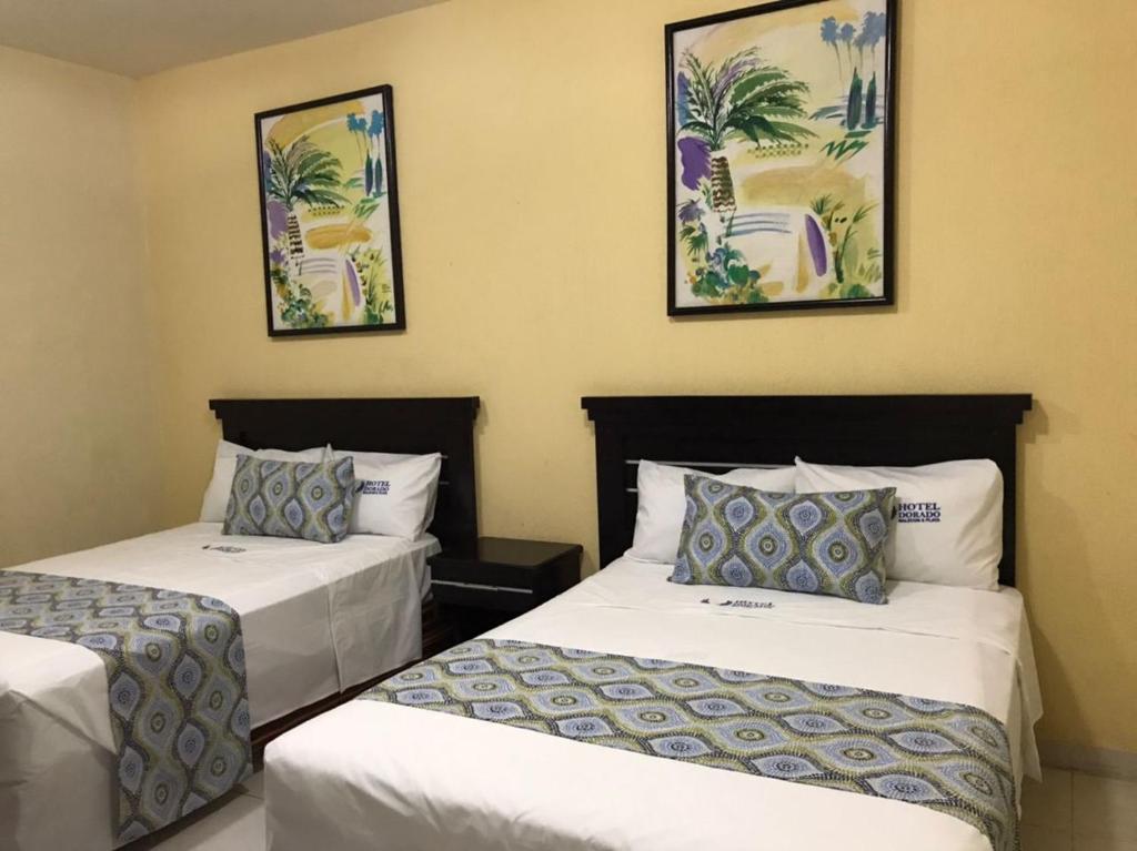 two beds in a hotel room with pictures on the wall at Hotel Dorado a una calle de Playa Regatas y el Malecon in Veracruz