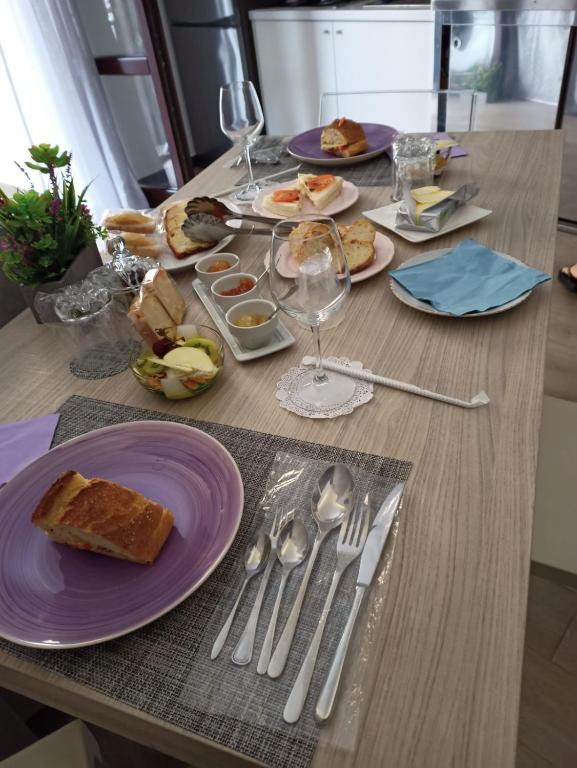 a table with purple plates of food and silverware at Sweet Dreams in San Vito lo Capo