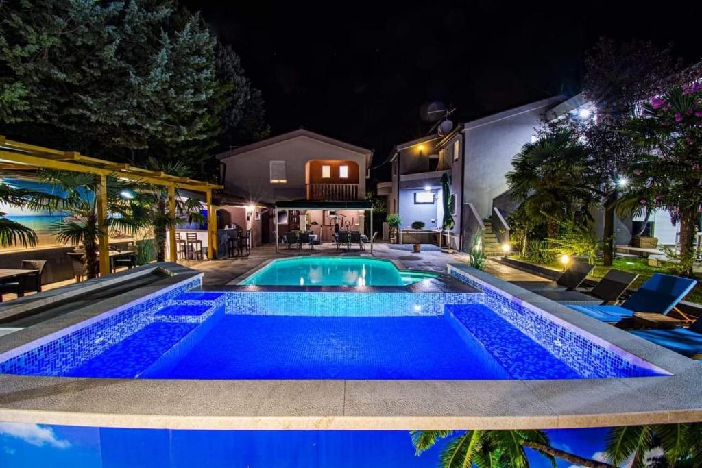a swimming pool in a backyard at night at Guest House Milicevic in Ljubuški