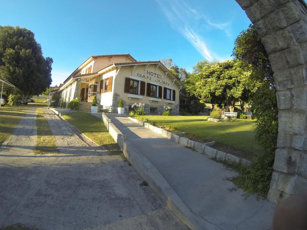 una casa con un arco frente a una calle en Hotel San Juan en Villa Giardino