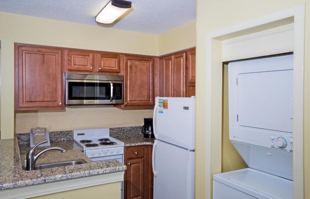 a kitchen with wooden cabinets and a white refrigerator at The Strand - A Boutique Resort in Myrtle Beach