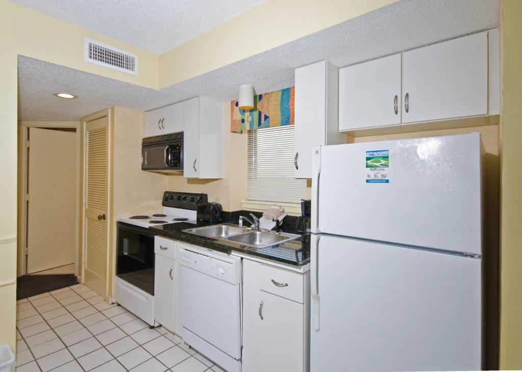 a kitchen with a white refrigerator and a sink at The Strand - A Boutique Resort in Myrtle Beach