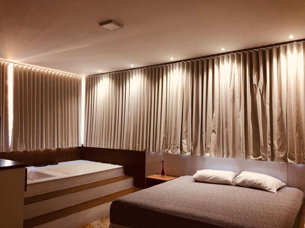 ポソス・デ・カルダスにあるHotel Pousada Beija Florのベッドルーム1室(カーテンの前にベッド2台付)