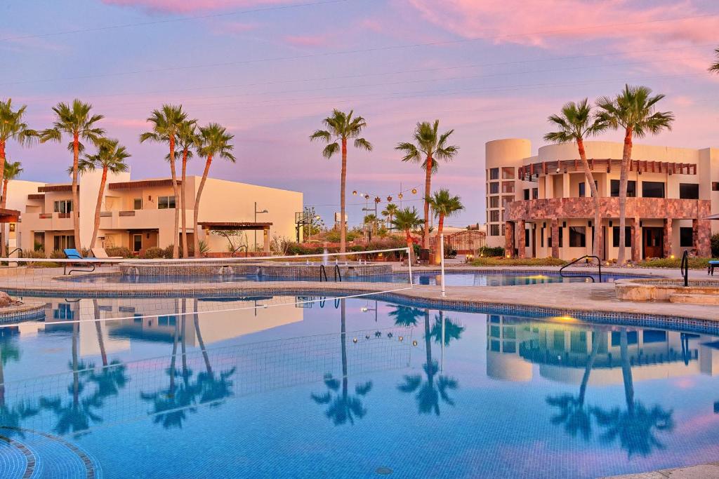 a swimming pool with palm trees in front of a building at Caracoles Homes in Puerto Peñasco