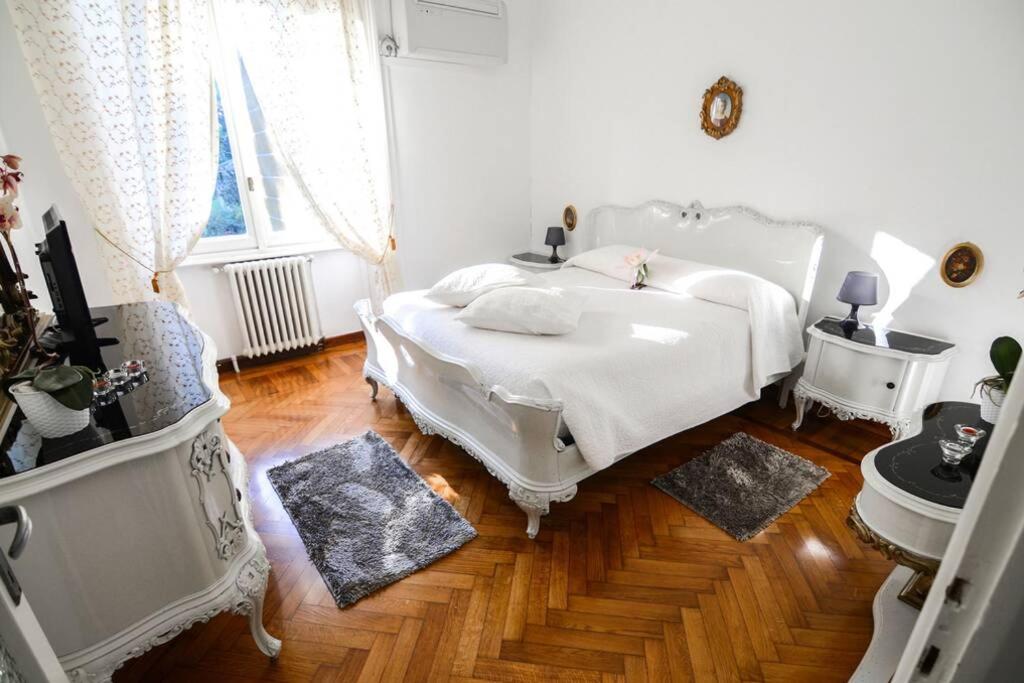 Schlafzimmer mit einem weißen Bett und Holzboden in der Unterkunft FREEDOM in Bellagio