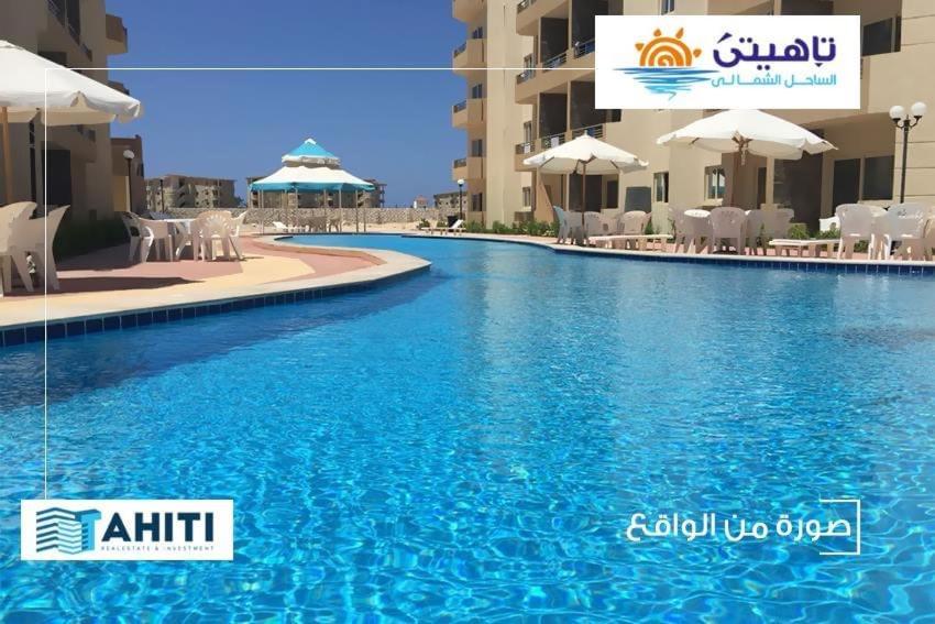 a swimming pool in front of a hotel at Tahiti North cost تاهيتي الساحل الشمالي in Al Ḩammām