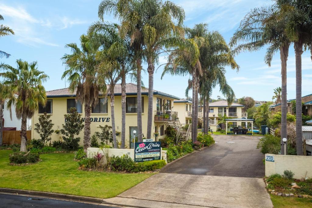 a house with palm trees in front of it at Ocean Drive Apartments in Merimbula