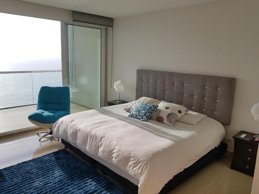 a bedroom with a large bed and a blue chair at H2 Hyatt Vista Mar!! in Cartagena de Indias