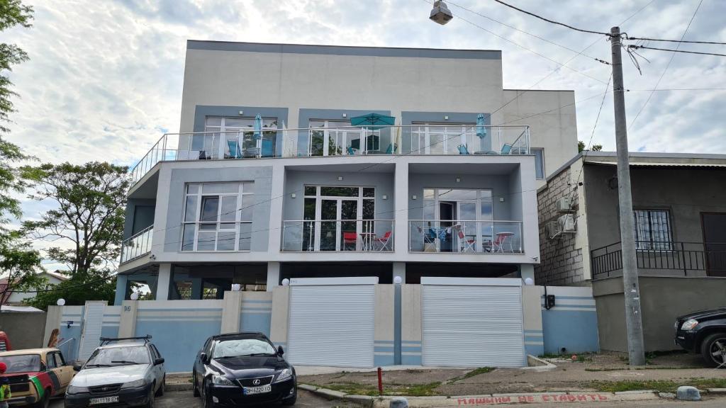 une maison blanche avec des voitures garées devant elle dans l'établissement Семейная Вилла Люстдорф, à Odessa