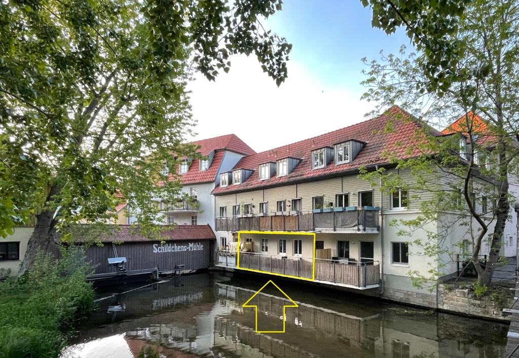 un edificio junto a un río con una flecha amarilla apuntando hacia arriba en Ferienwohnung Blickfang - Modernes Apartment direkt in der Altstadt von Erfurt mit Balkon - beste Lage und Aussicht, en Erfurt