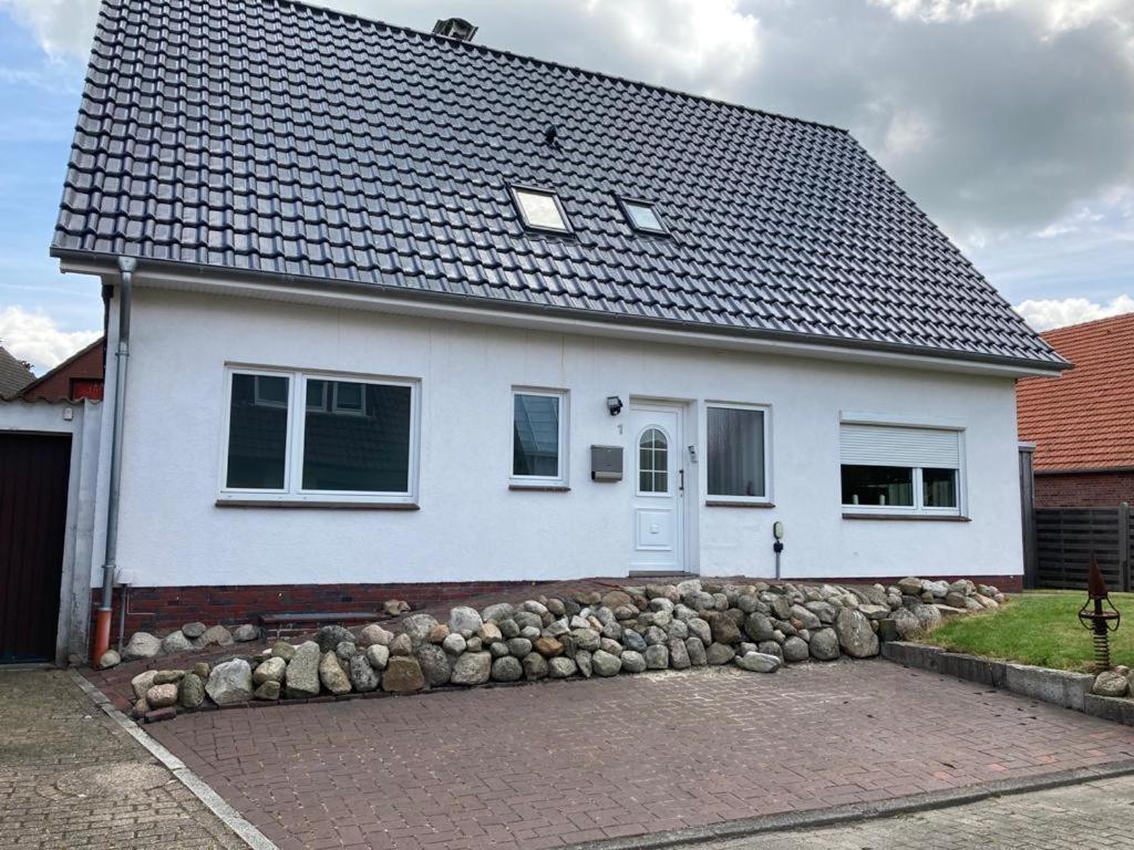 a white house with a rock wall in front of it at Zur Mühle in Varel