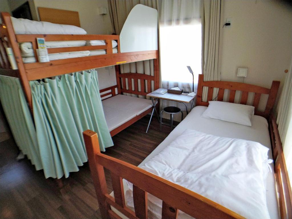 a bedroom with two bunk beds and a desk at Hiroshima Saijo Youth Hostel in Higashihiroshima